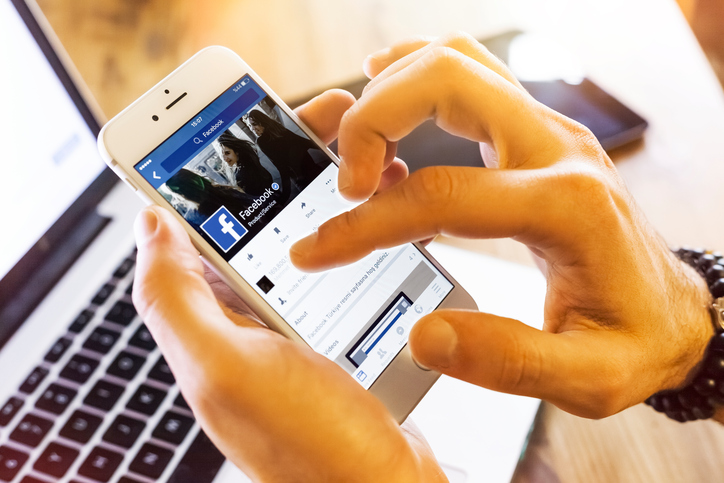 man using Facebook on mobile phone