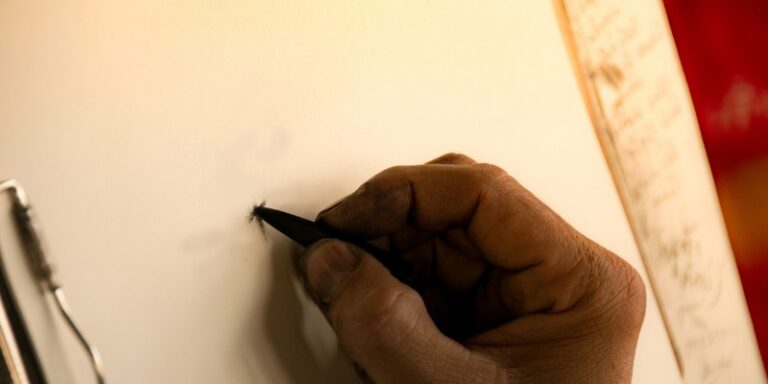 Close up of hand holding pencil on paper