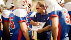 Football coach going over play to football players.